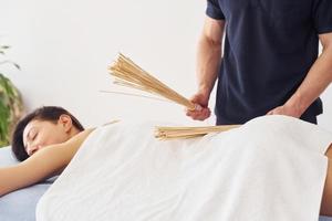 Special equipment. Young woman is lying down when man doing massage of her body at spa photo