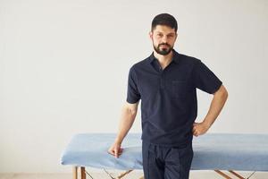 Serious man in shirt standing indoors against white background photo