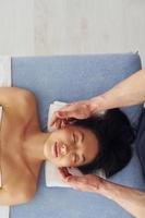 Top view. Young woman is lying down when man doing massage of her body at spa photo
