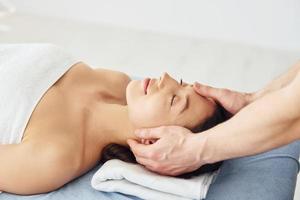 Head massage. Young woman is lying down when man doing procedure to her in spa photo