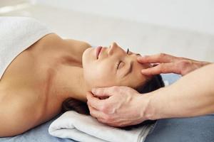 Head massage. Young woman is lying down when man doing procedure to her in spa photo