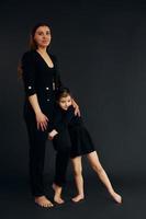 Mother and daughter is together in the studio against black background photo