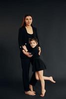 Mother and daughter is together in the studio against black background photo