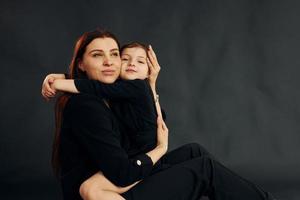 madre e hija están juntas en el estudio con fondo negro foto