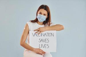 Young woman in mask is sits after vaccine injection indoors photo