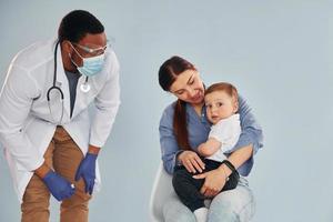 Mother with her little son is in the hospital with african american doctor photo