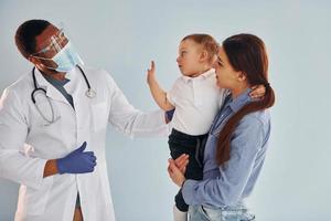 madre con su hijo pequeño está en el hospital con un médico afroamericano foto