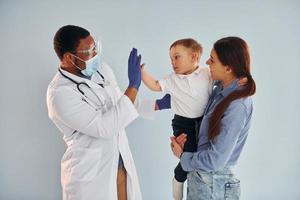 Mother with her little son is in the hospital with african american doctor photo