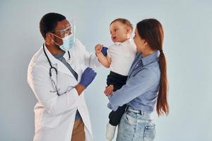 Mother with her little son is in the hospital with african american doctor photo