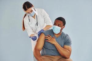 Female doctor giving injection to african american man at hospital photo