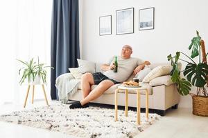 Funny overweight man in casual clothes is indoors at home photo