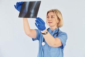 Holds x-ray. Middle-aged professional female doctor in uniform and with stethoscope photo