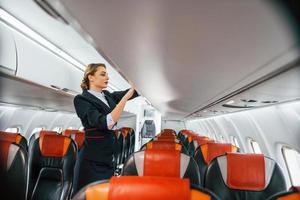 Asientos vacíos. joven azafata en el trabajo en el avión de pasajeros foto