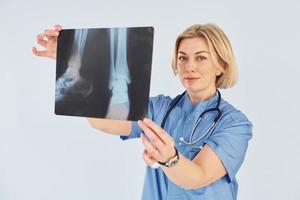 Holds x-ray. Middle-aged professional female doctor in uniform and with stethoscope photo