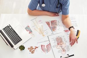 Close up view of female doctor that works by the table with pictures and laptop photo