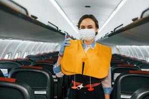 Safety instructions. Young stewardess on the work in the passanger airplane photo