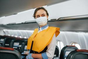 Safety instructions. Young stewardess on the work in the passanger airplane photo