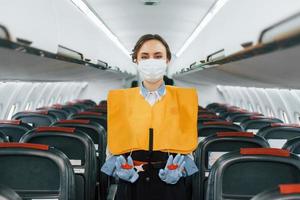 instrucciones de seguridad. joven azafata en el trabajo en el avión de pasajeros foto