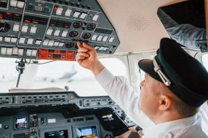 Close up view. Pilot on the work in the passenger airplane. Preparing for takeoff photo