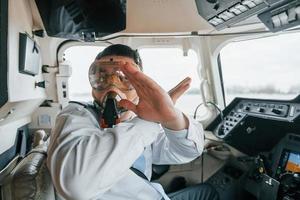 en máscara de oxígeno. piloto en el trabajo en el avión de pasajeros. preparándose para el despegue foto