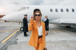 A young woman in yellow clothes is accompanied by an airline workers photo