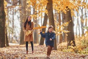 Playing with leaves. Mother with her son is having fun outdoors in the autumn forest photo