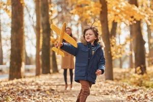 Active weekend time spending. Mother with her son is having fun outdoors in the autumn forest photo