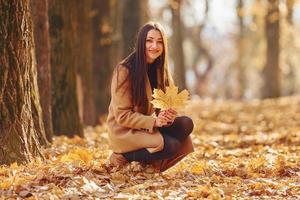 mujer con abrigo ha caminado en el bosque de otoño foto