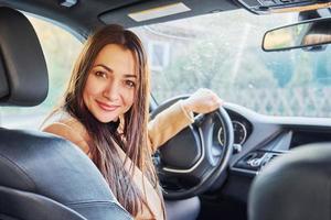 Vehicle interior. Woman is sitting in modern black colored automobile photo