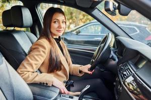 Vehicle interior. Woman is sitting in modern black colored automobile photo