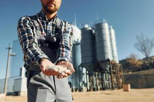 Holding soil. Construction worker in uniform is outdoors near the factory photo