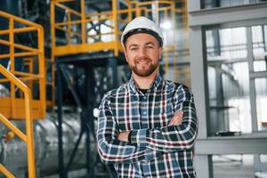 posando para la cámara. trabajador de la construcción en uniforme está en la fábrica foto