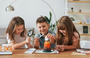 Working on the volcano project. Kids having fun in the domestic room at daytime together photo