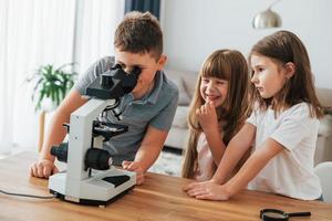With microscope. Kids having fun in the domestic room at daytime together photo