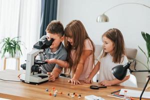 Using microscope. Kids having fun in the domestic room at daytime together photo