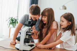 With microscope. Kids having fun in the domestic room at daytime together photo