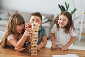 Jumbling tower game. Kids having fun in the domestic room at daytime together photo