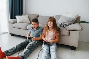 jugando videojuegos. niños divirtiéndose juntos en la sala doméstica durante el día foto