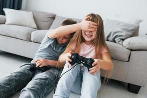 sentado en el suelo y jugando videojuegos. niños divirtiéndose juntos en la sala doméstica durante el día