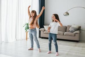 Dancing together. Kids having fun in the domestic room at daytime photo