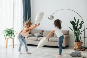 Pillow fight. Kids having fun in the domestic room at daytime together photo