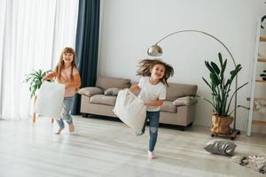 Running with pillows. Kids having fun in the domestic room at daytime together photo