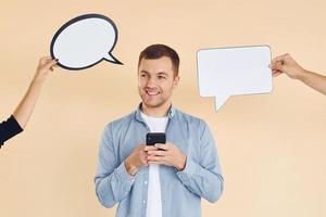 Holding smartphone. Many ideas. Man standing in the studio with empty signs for the text photo