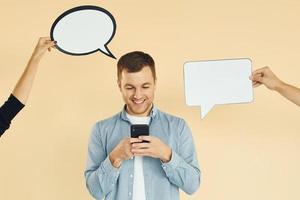 Holding smartphone. Many ideas. Man standing in the studio with empty signs for the text photo