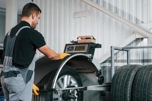 Fixing the tire. Man in uniform is working in the auto service photo