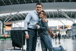 Embracing each other. Young couple is in the airport together photo