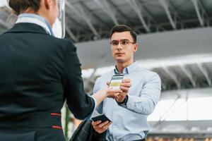 Man showing vaccination certificate. Young businessman in formal clothes is in the airport at daytime photo