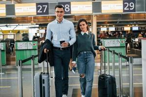 caminando hacia adelante pareja joven está en el aeropuerto juntos foto