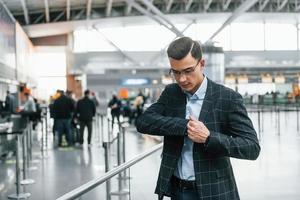 Taking out the documents. Young businessman in formal clothes is in the airport at daytime photo