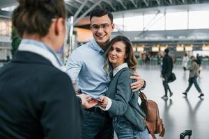 empleado revisando los documentos. pareja joven está en el aeropuerto juntos foto